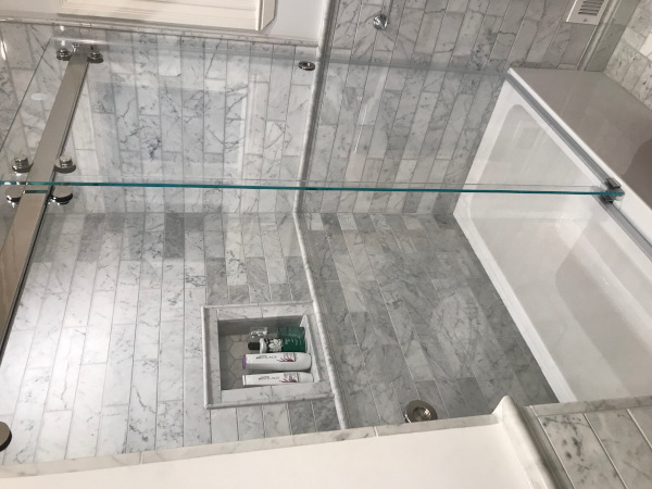 Classic marbled tile shower and bathtub with frameless bypass sliding shower doors.